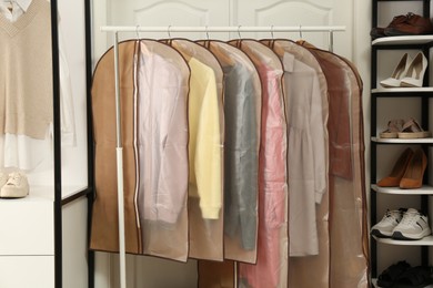 Garment bags with clothes on rack in dressing room