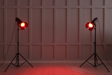 Photo of Bright red spotlights near wall indoors, space for text