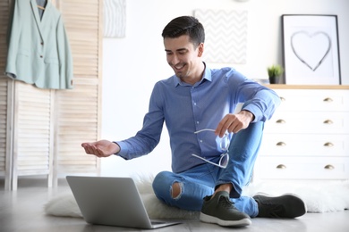 Young blogger with laptop on floor at home