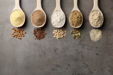 Photo of Spoons with different types of flour and ingredients on grey background, top view. Space for text