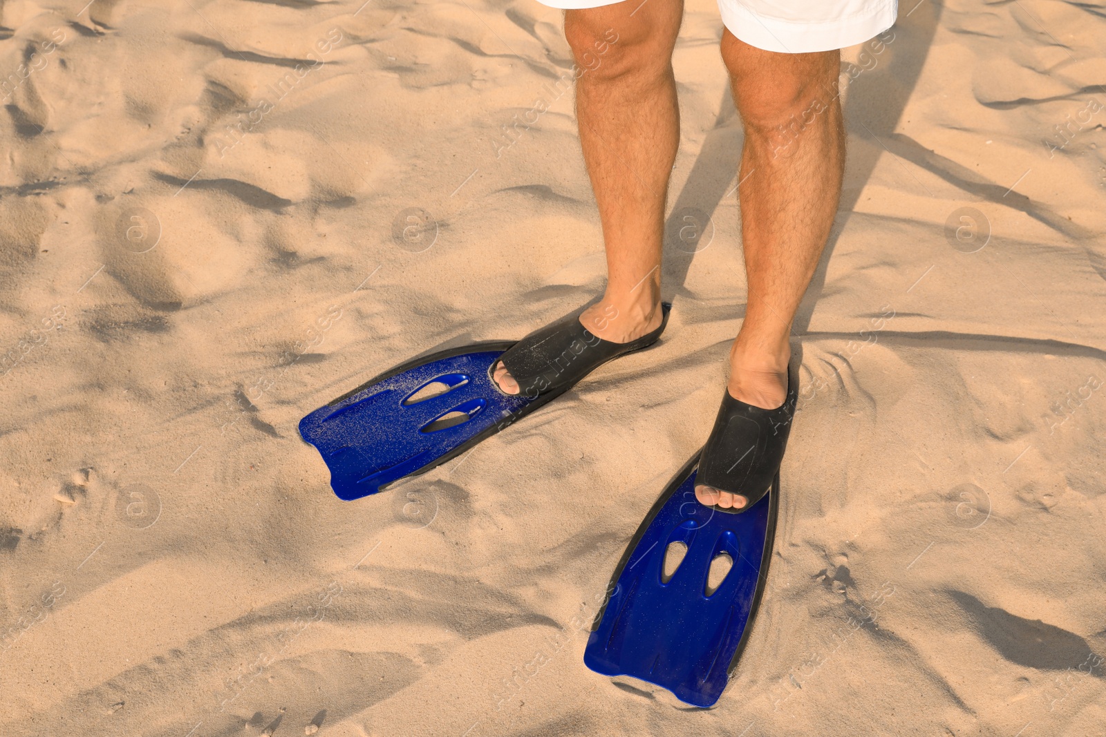 Photo of Man in blue flippers on sand, closeup view