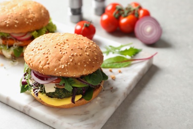 Board with tasty vegetarian burgers on table