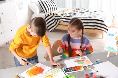 Photo of Little children painting picture at table indoors