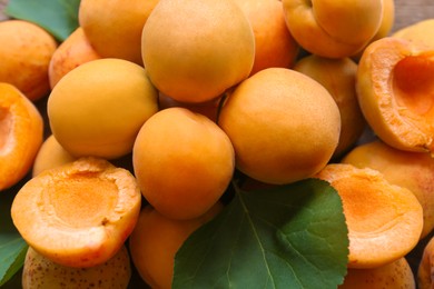 Photo of Top view of delicious ripe apricots with green leaves, closeup