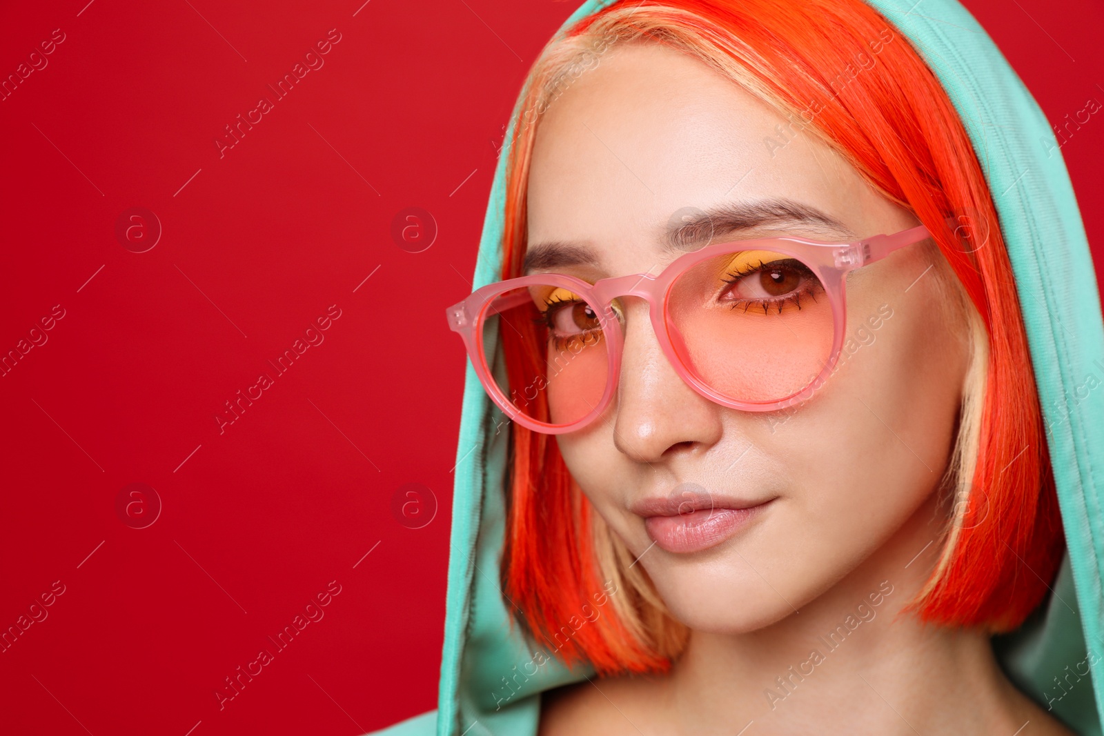 Photo of Beautiful young woman with bright dyed hair on red background, closeup. Space for text