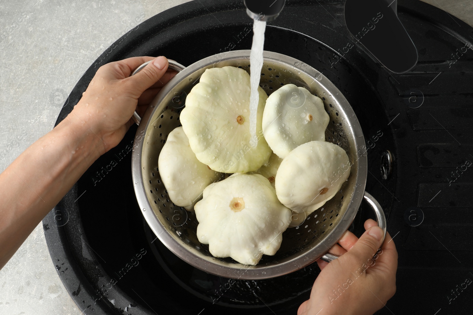 Photo of Woman washing pattypan squashes above sink, closeup