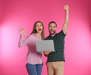 Emotional young people with laptop celebrating victory on color background