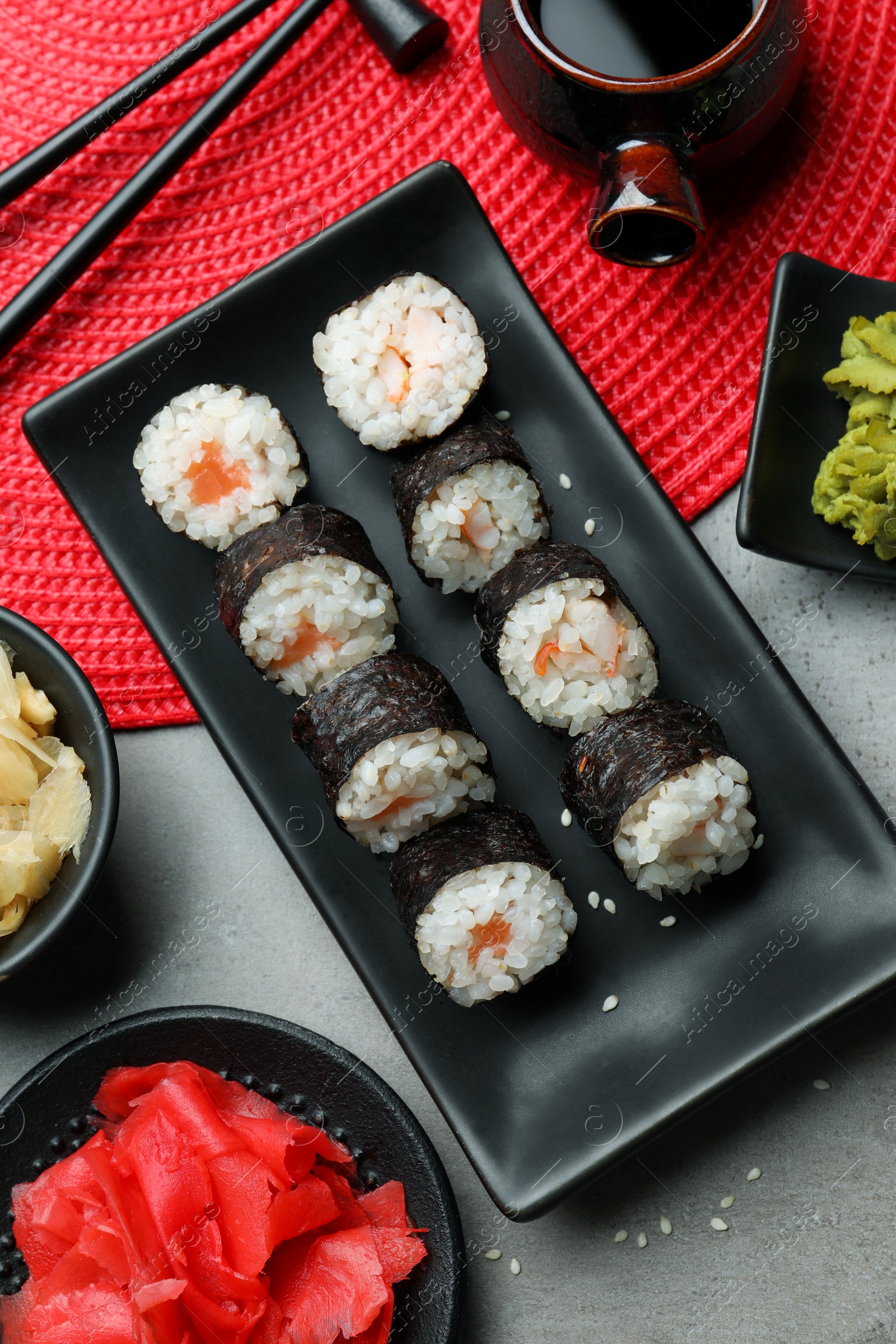 Photo of Tasty sushi rolls served on grey table, flat lay