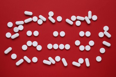 Photo of Sad and happy emoticons made of antidepressants on red background, flat lay