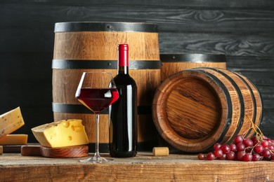 Photo of Winemaking. Composition with tasty wine and barrels on wooden table