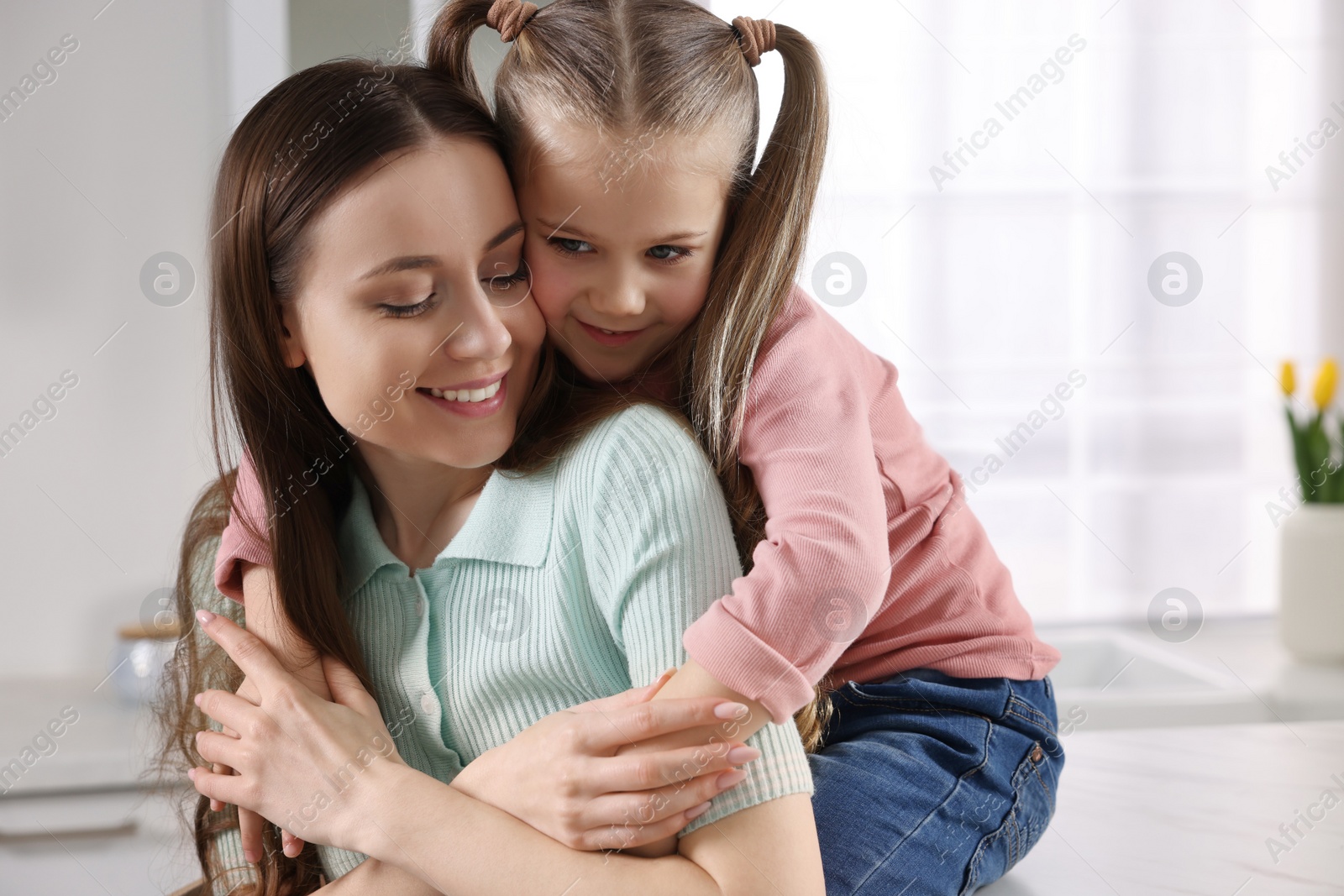 Photo of Happy mother with her cute daughter in kitchen