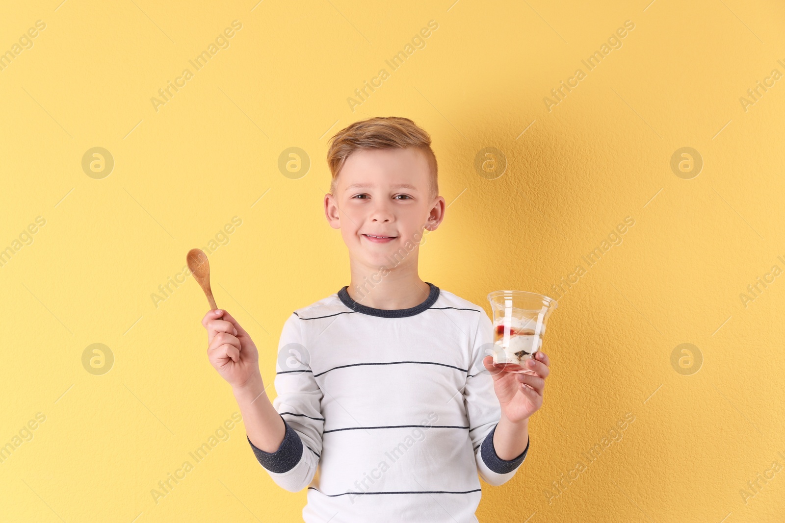 Photo of Little boy with yogurt on color background