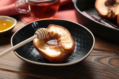Photo of Tasty baked quince with honey in bowl on wooden table