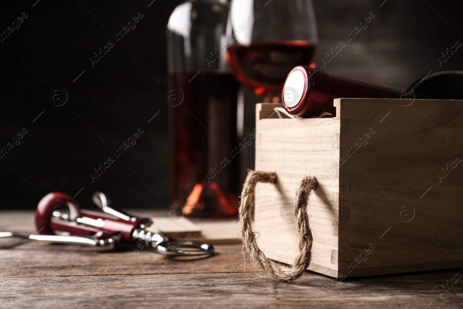 Photo of Open wooden crate with bottle of wine and corkscrew on table, space for text
