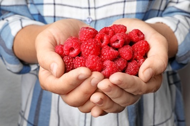 Photo of Woman holding heap of delicious ripe raspberries, closeup