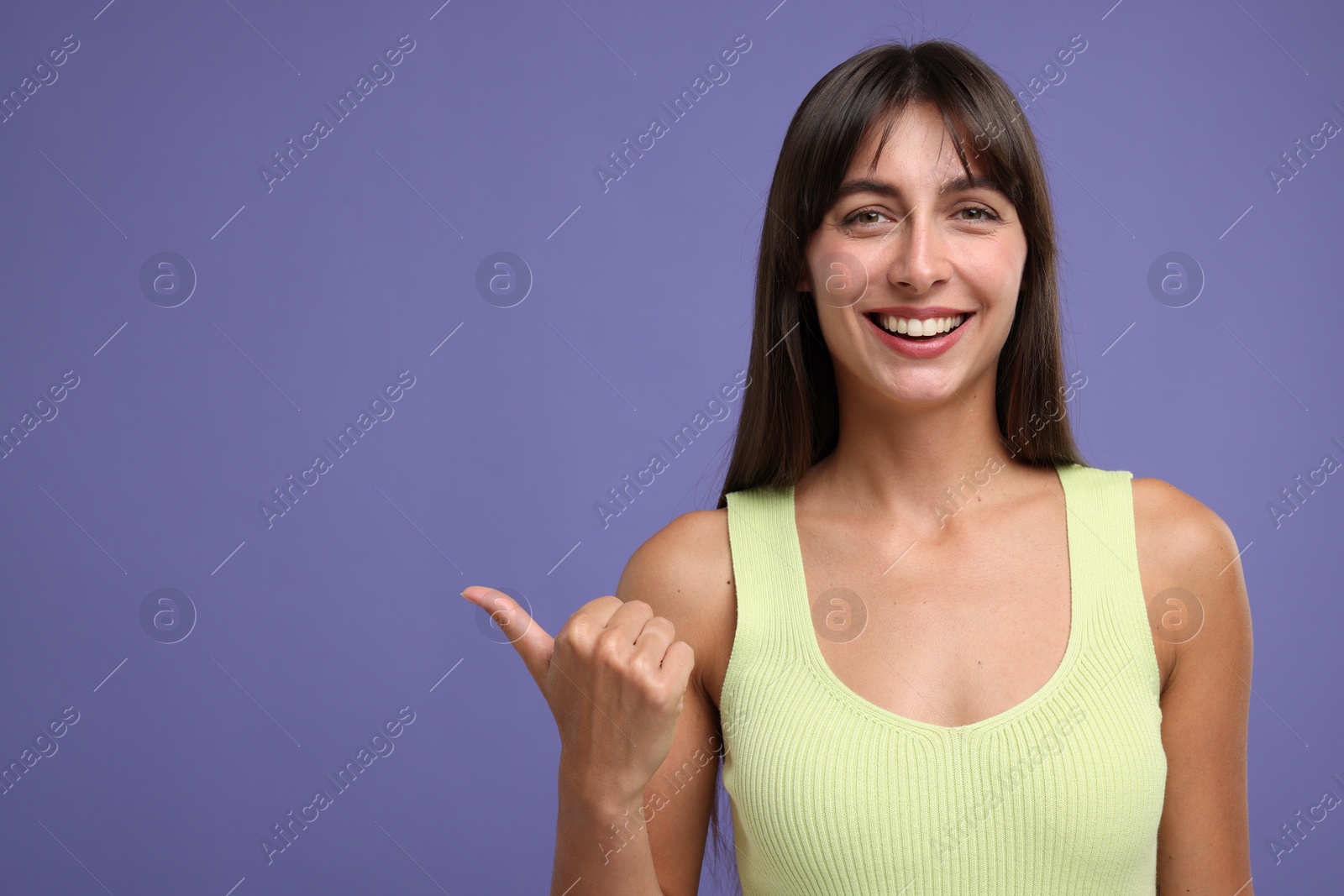 Photo of Special promotion. Happy woman pointing at something on violet background, space for text
