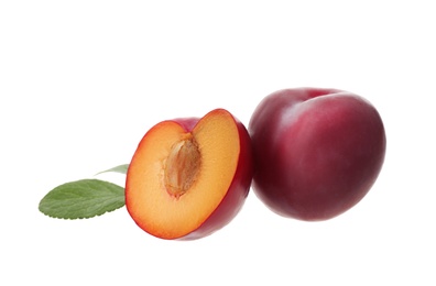 Whole and cut ripe plums with green leaves isolated on white