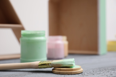 Photo of Brush with paint on grey wooden table, closeup