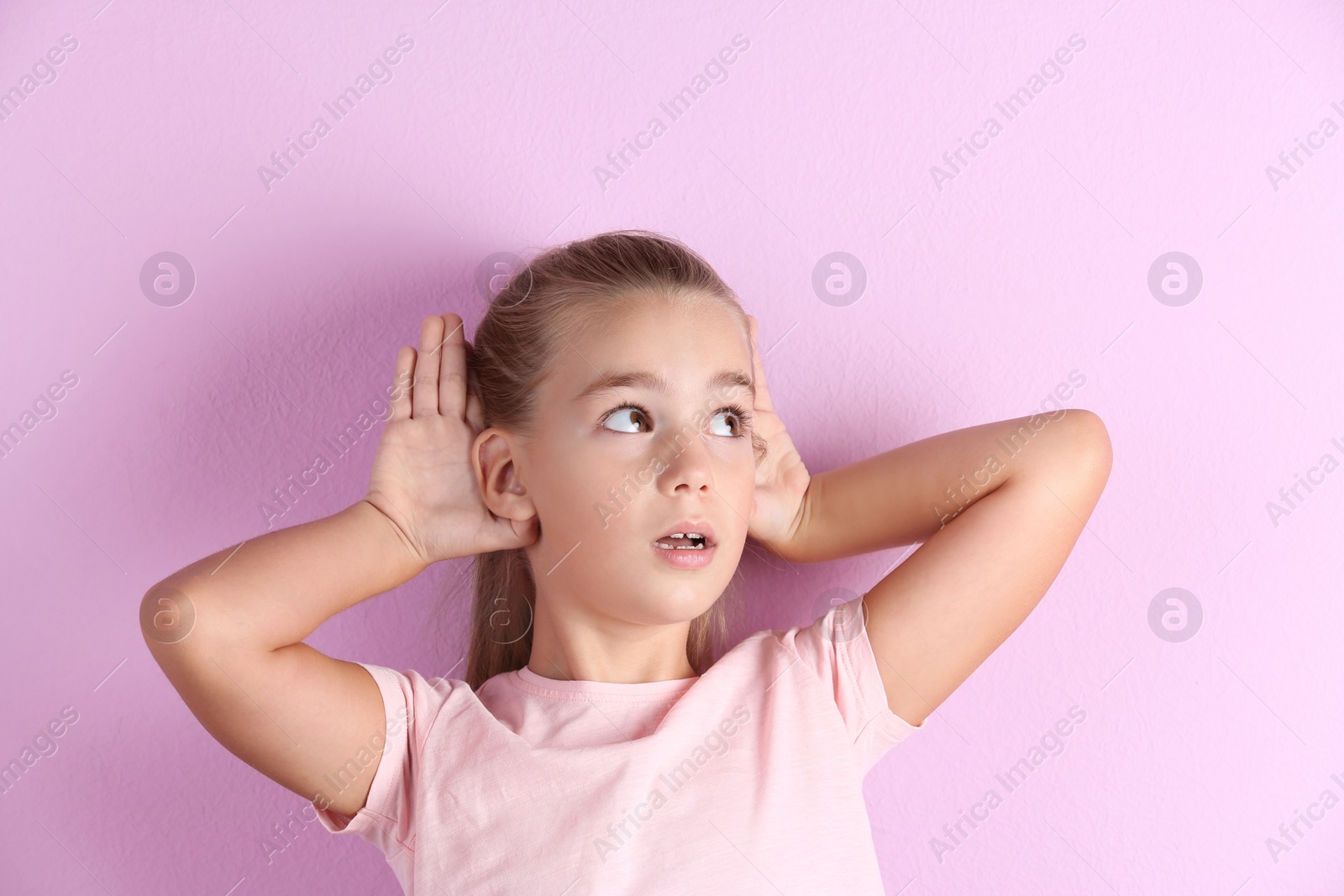 Photo of Cute little girl with hearing problem on color background