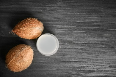 Photo of Glass of coconut water and fresh nuts on wooden background, top view