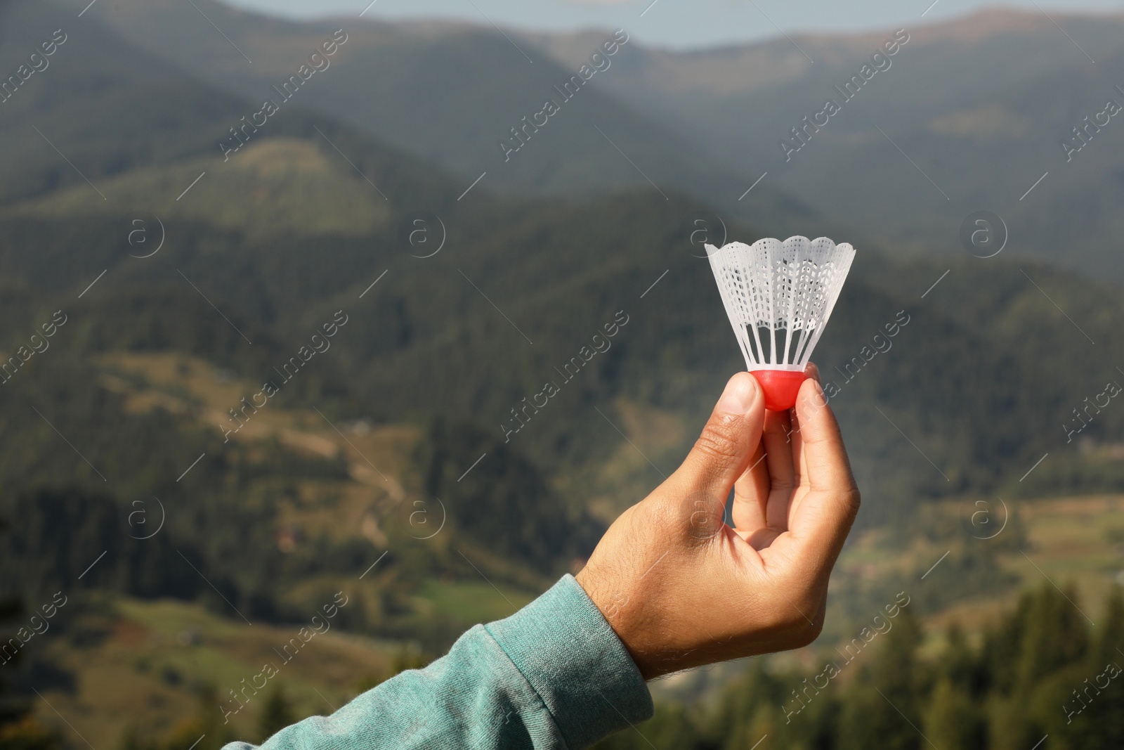 Photo of Man with badminton shuttlecock in mountains, closeup. Space for text