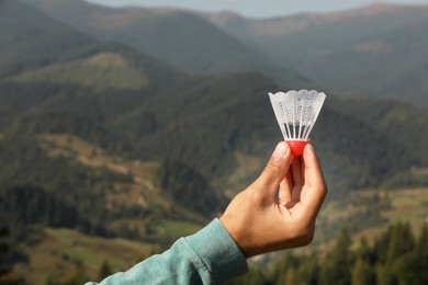 Man with badminton shuttlecock in mountains, closeup. Space for text