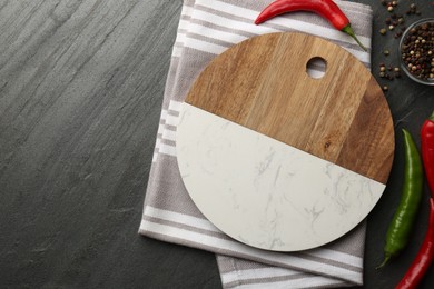 Photo of Cutting board, spices and kitchen towel on dark grey table, flat lay. Space for text