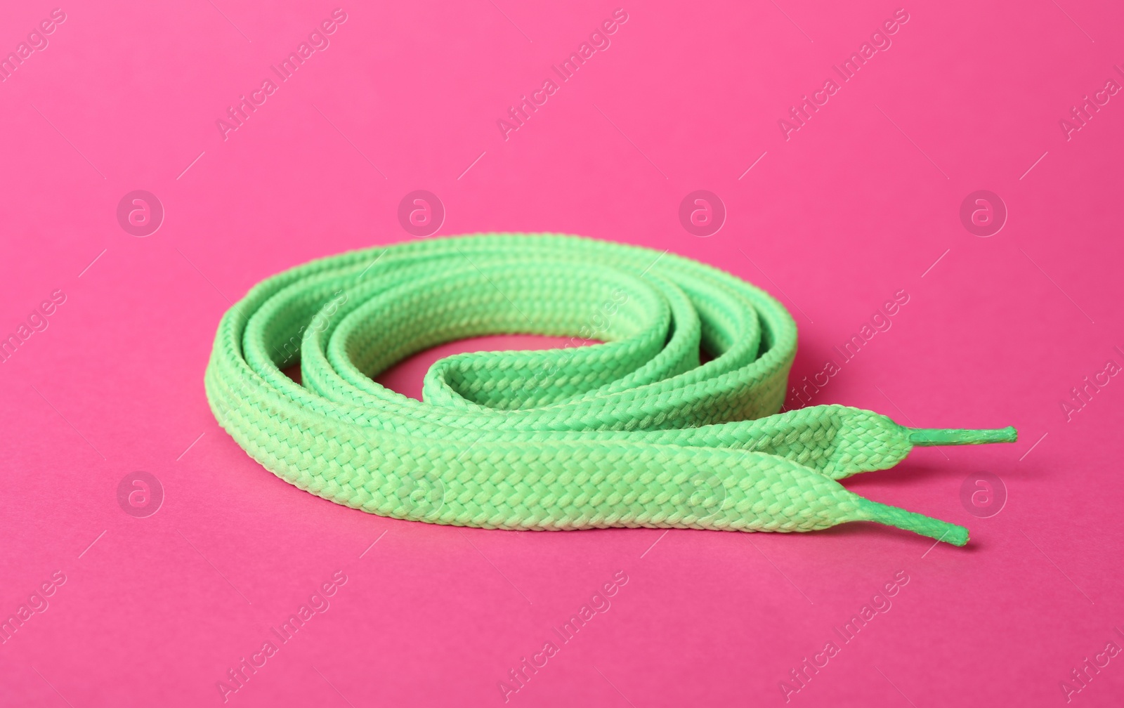 Photo of Mint shoe lace on pink background. Stylish accessory