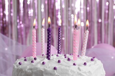 Delicious cake with cream and burning candles on color background, closeup