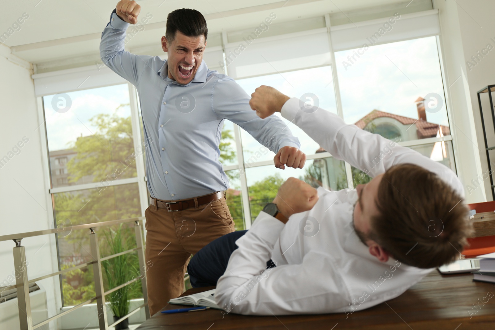 Photo of Emotional colleagues fighting in office. Workplace conflict