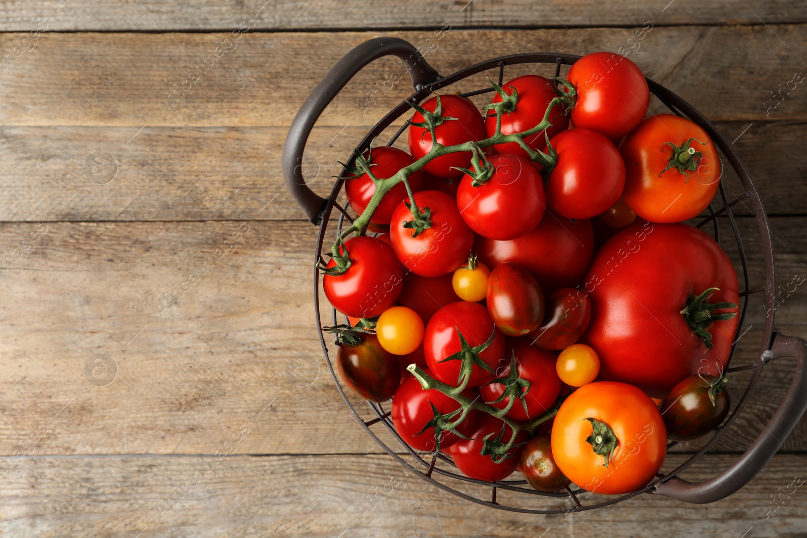 Photo of Fresh ripe tomatoes in basket on wooden table, top view. Space for text