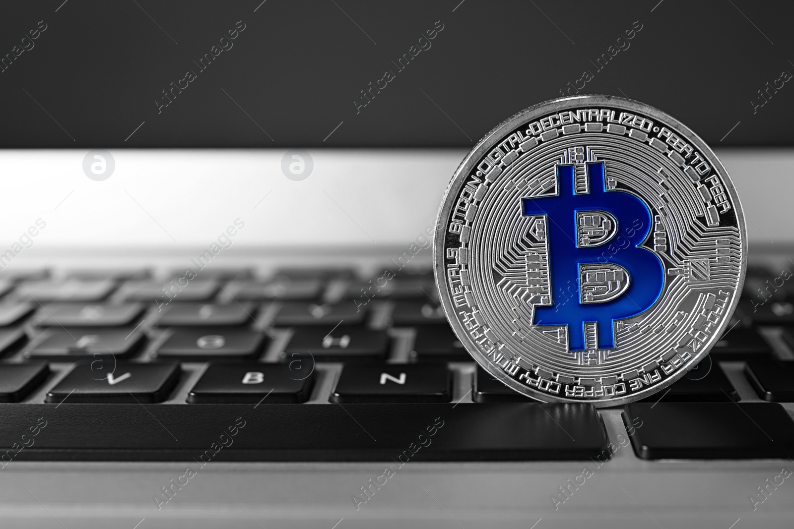 Photo of Silver bitcoin on computer keyboard, space for text. Digital currency