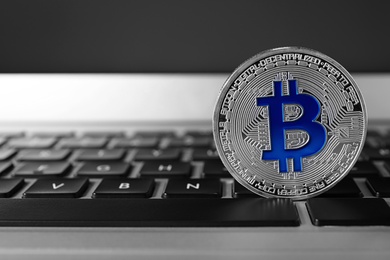 Silver bitcoin on computer keyboard, space for text. Digital currency