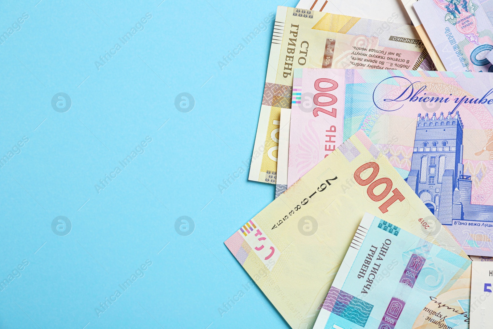 Photo of Ukrainian money on light blue background, flat lay. Space for text