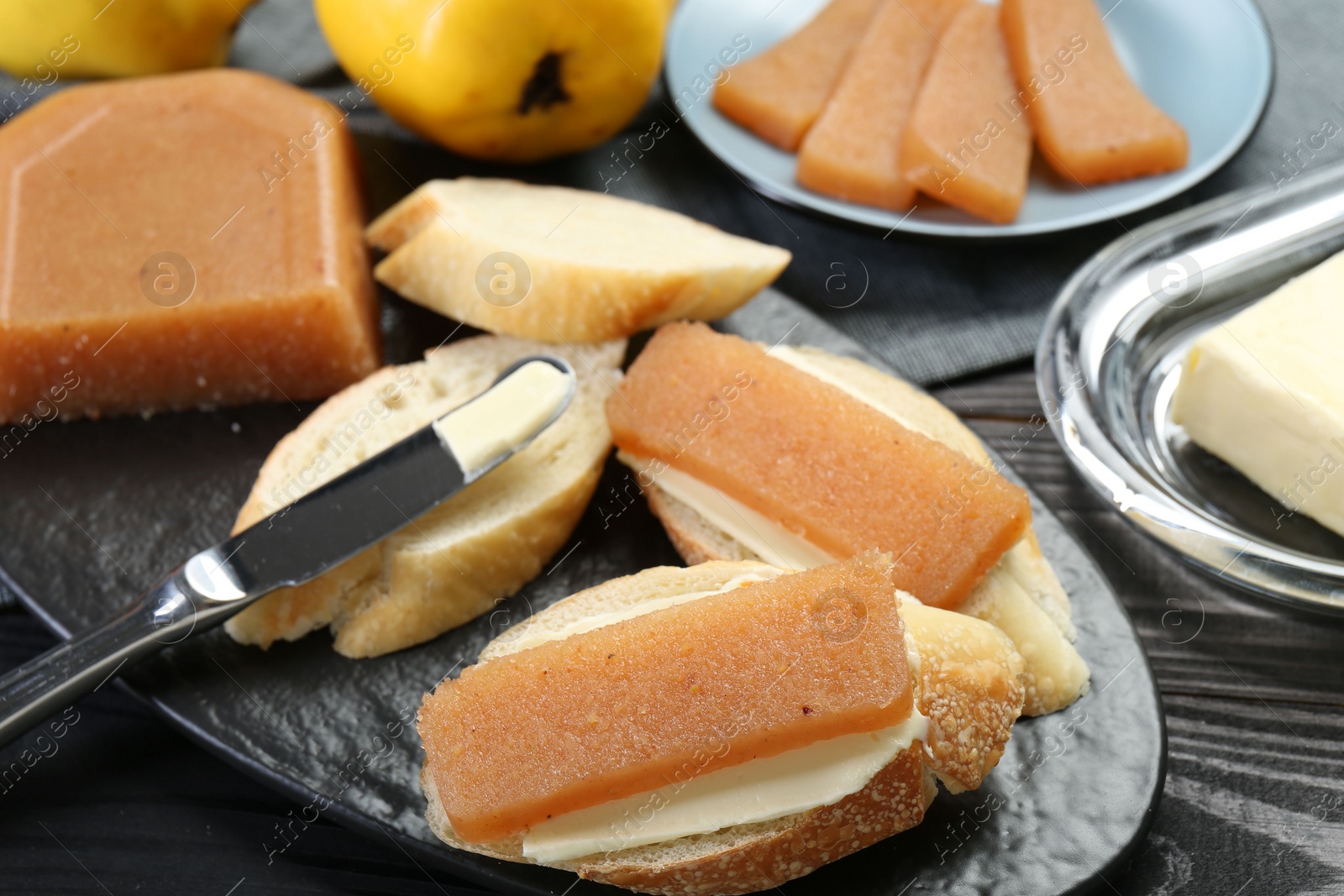 Photo of Tasty sandwiches with quince paste served on black wooden table, closeup