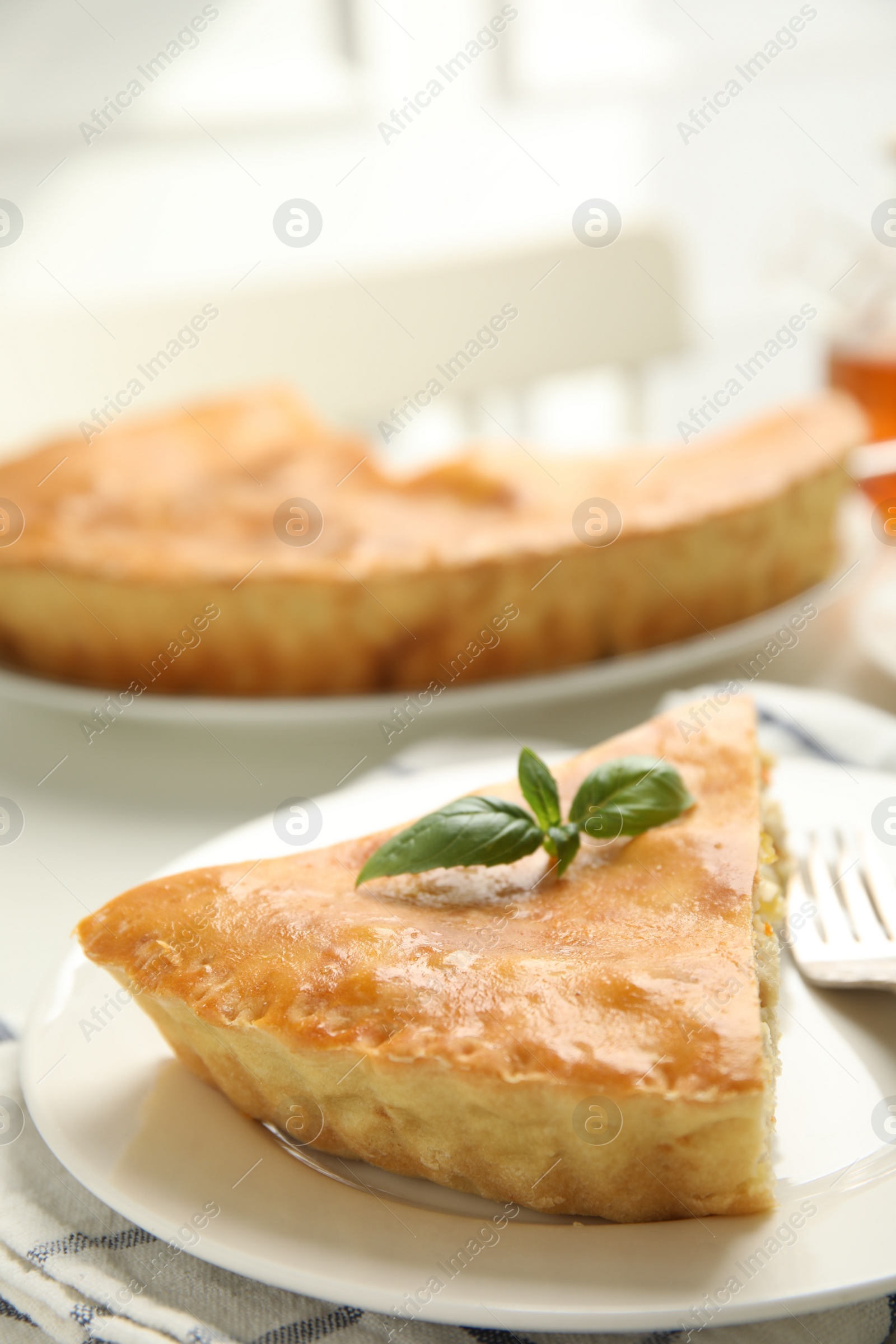 Photo of Piece of delicious pie with meat and basil on white table