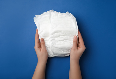 Woman with diapers on blue background, closeup
