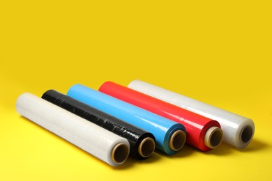 Photo of Different plastic stretch wrap films on yellow background