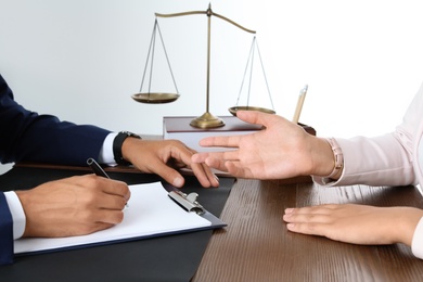 Photo of Male lawyer working with client at table in office