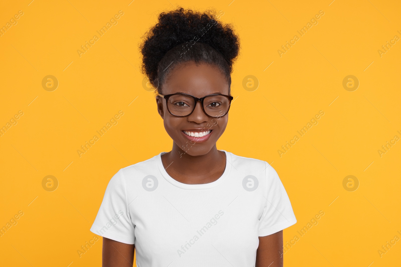 Photo of Portrait of happy young woman in eyeglasses on orange background