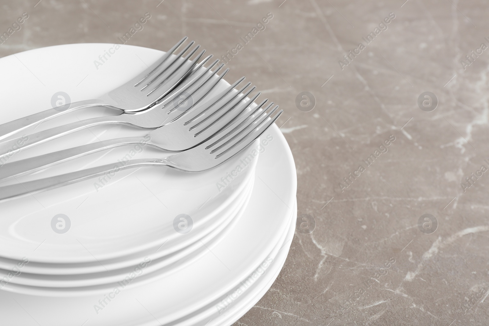 Photo of Stack of ceramic dishware with cutlery on grey background