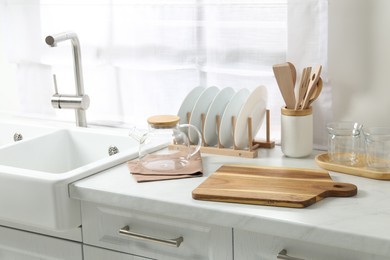 Photo of Wooden cutting boards, other cooking utensils and dishware on white countertop in kitchen