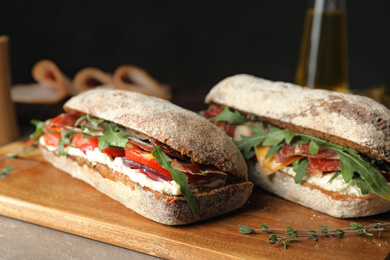 Photo of Delicious sandwiches with fresh vegetables and prosciutto on table