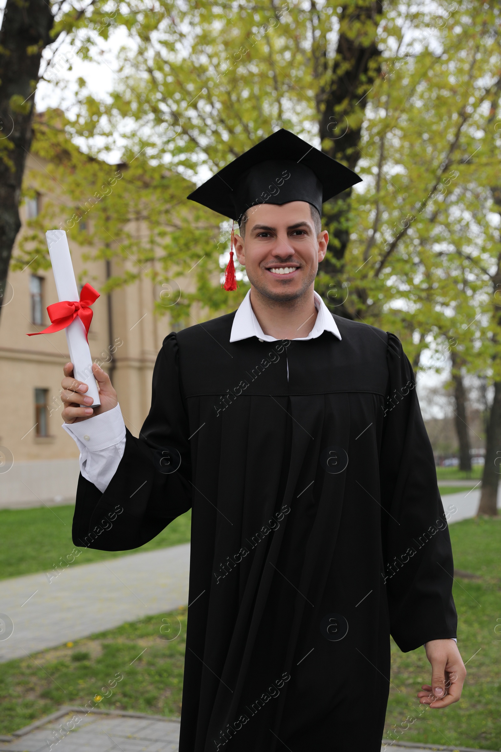 Photo of Happy student with diploma after graduation ceremony outdoors