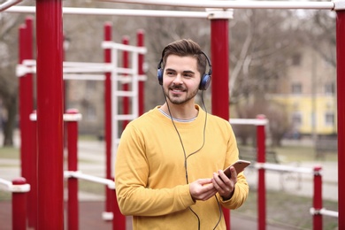 Photo of Young man with headphones listening to music on sports ground