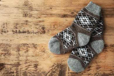 Photo of Knitted socks on wooden background, flat lay with space for text