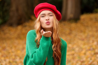 Portrait of beautiful woman blowing kiss in autumn park