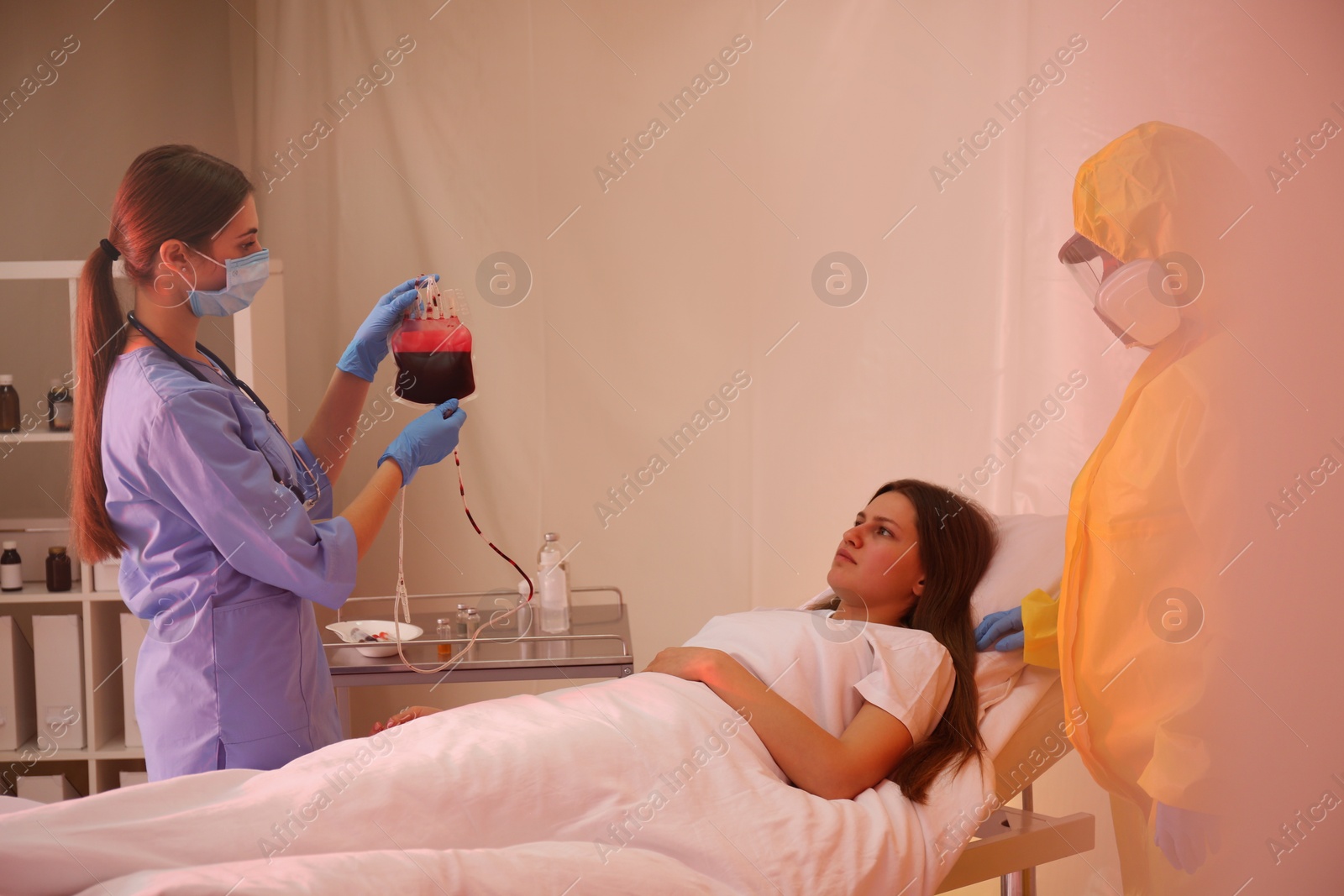 Photo of Professional paramedics examining patient with virus in quarantine ward