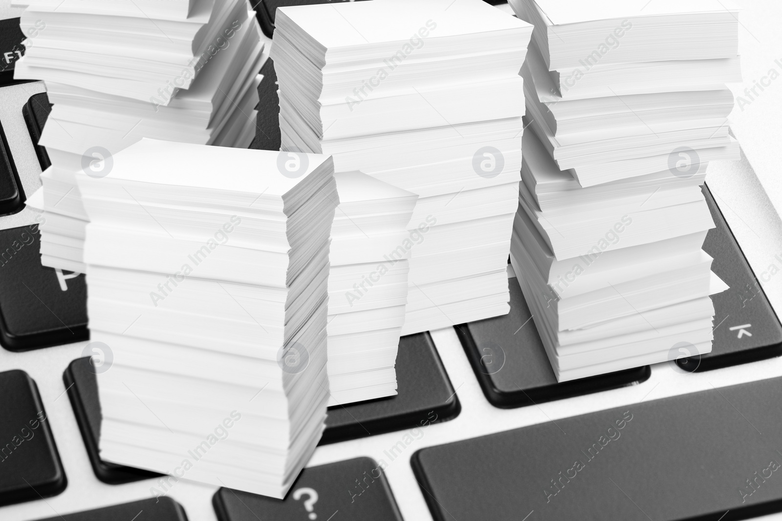 Image of Digital archive. Laptop keyboard with downsized stacked papers, closeup