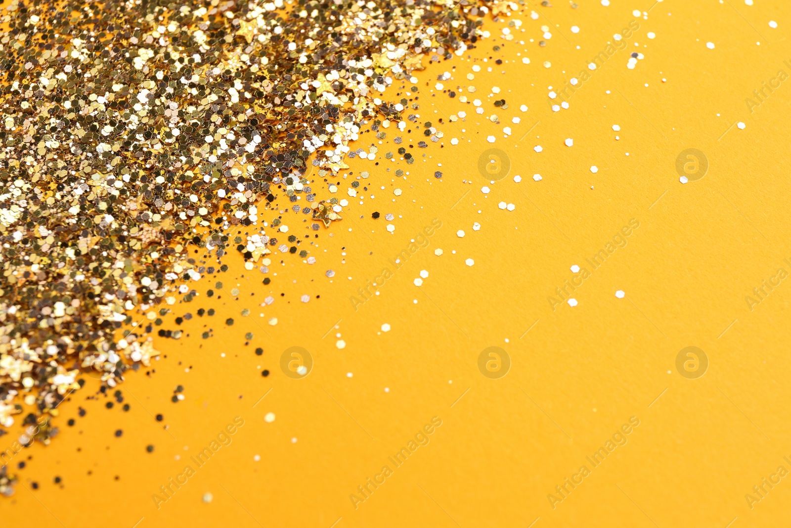 Photo of Shiny bright golden glitter on pale orange background. Space for text